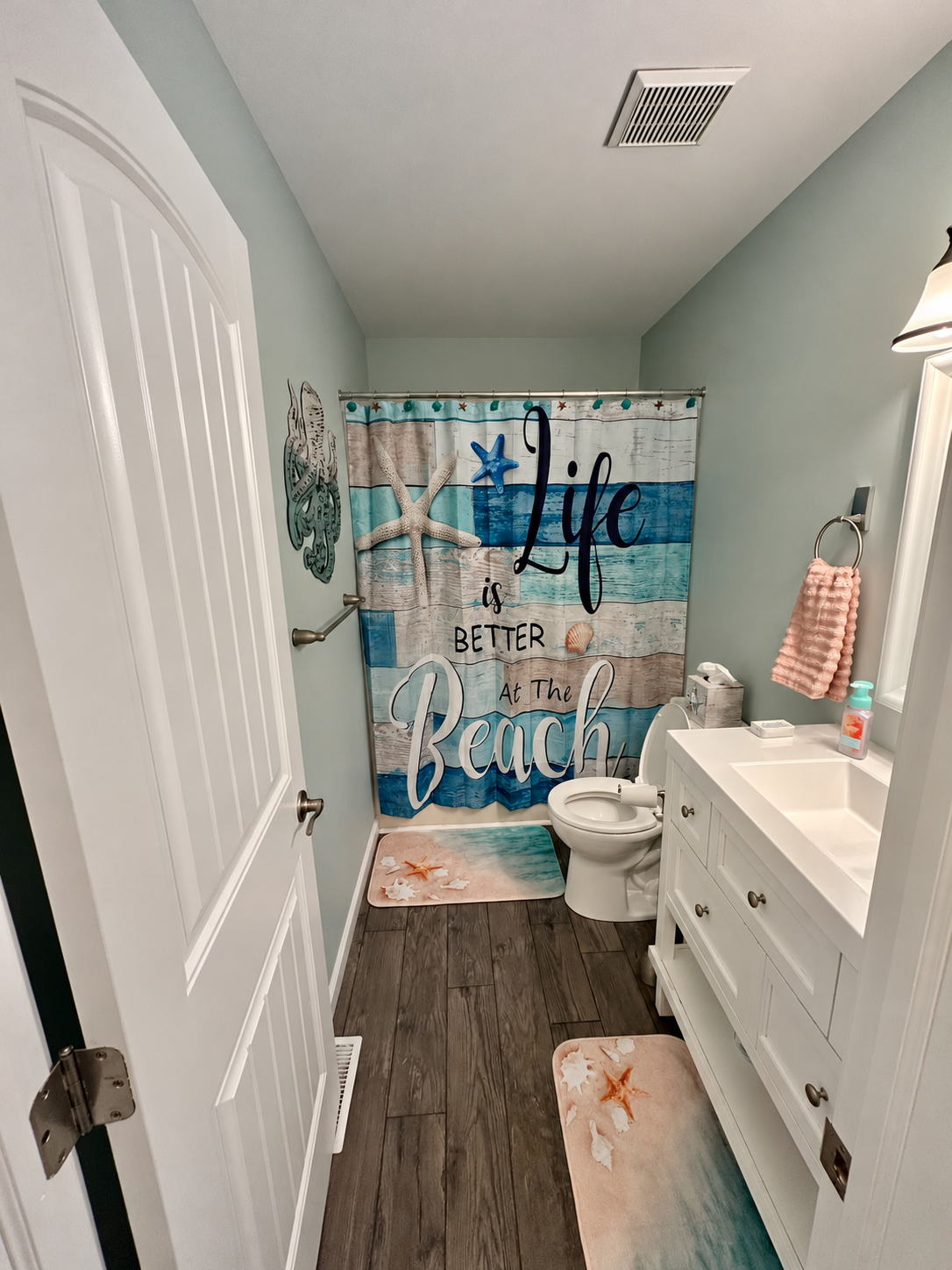 Full bathroom with white vanity and aqua beach-themed shower curtain