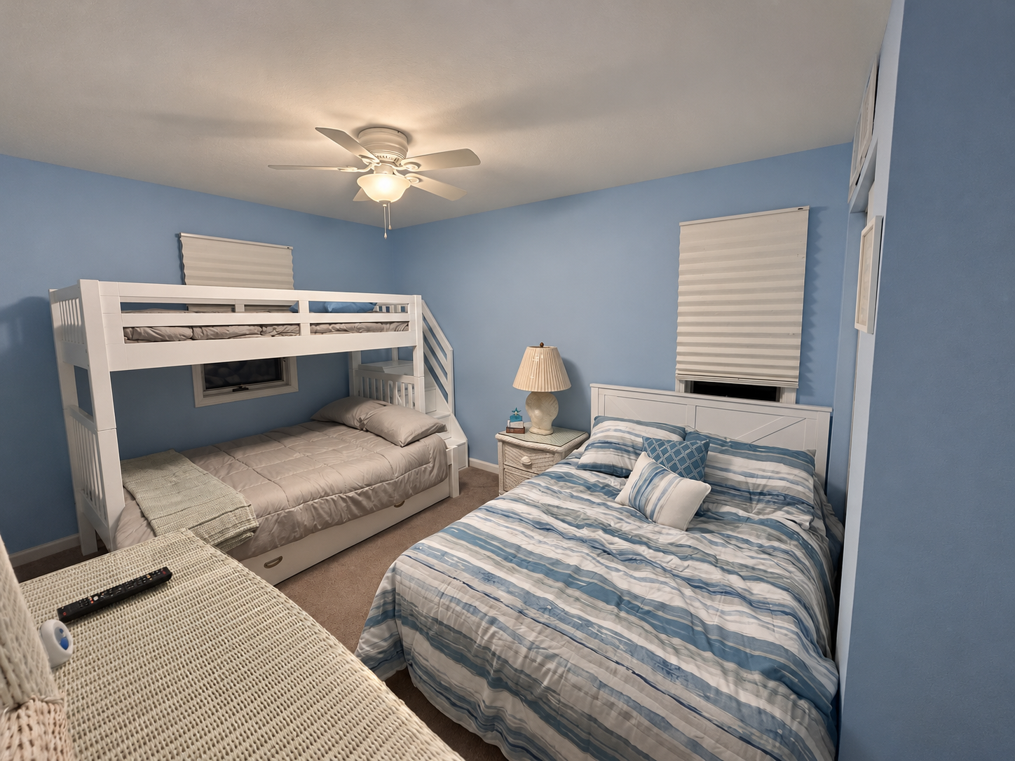Second bedroom with white bunk beds and a separate bed in blue coastal decor