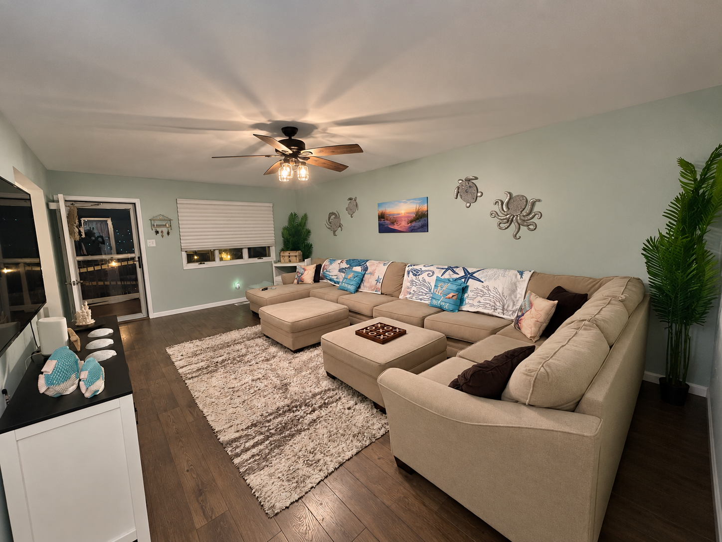 Spacious living room with wraparound sectional, beach-inspired decor and a large rug